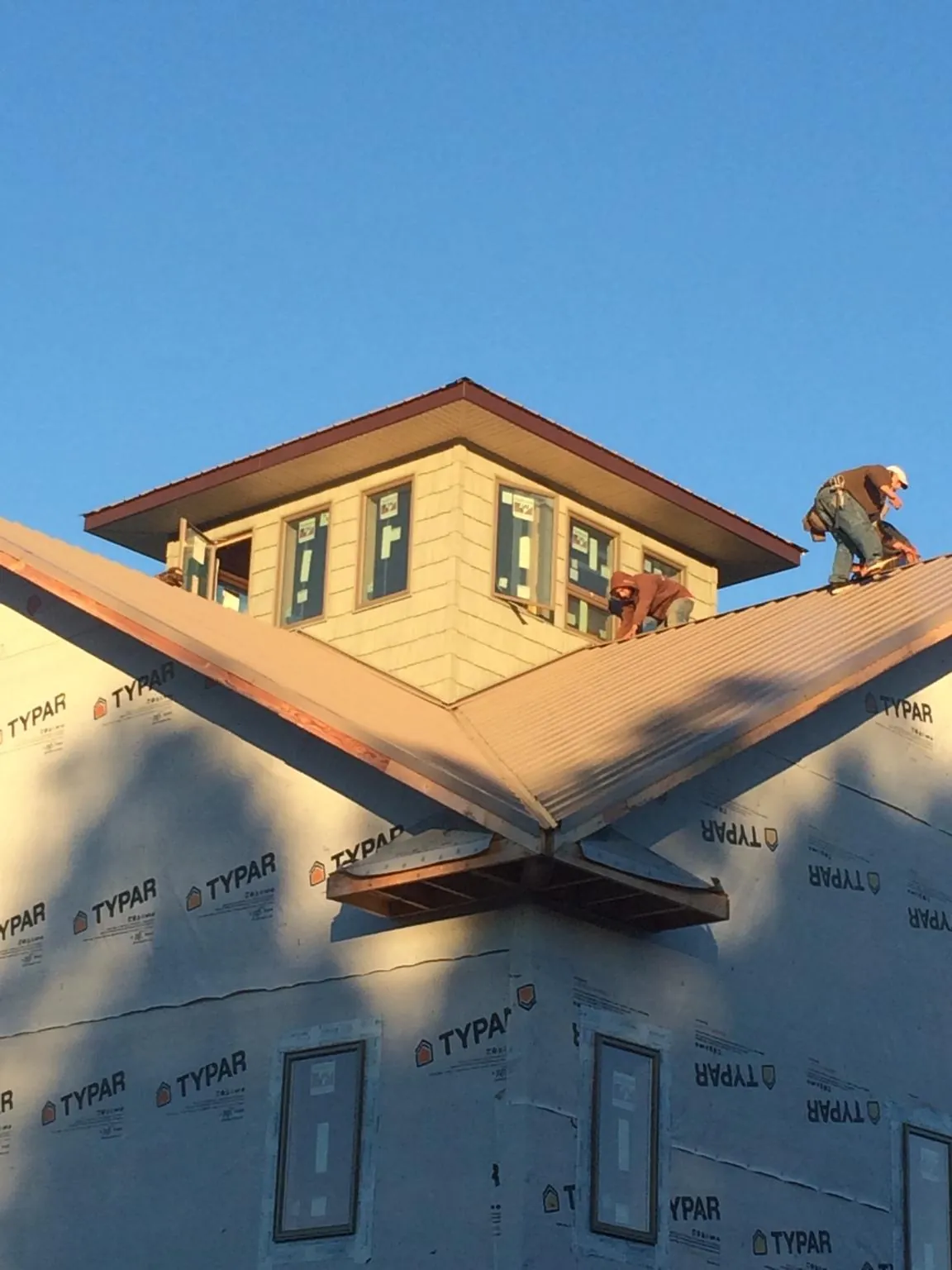 Roofers working around a rooftop cupola on a new metal roof at sunset — Roof Waterproofing in Chesterfield by Roofing Brothers